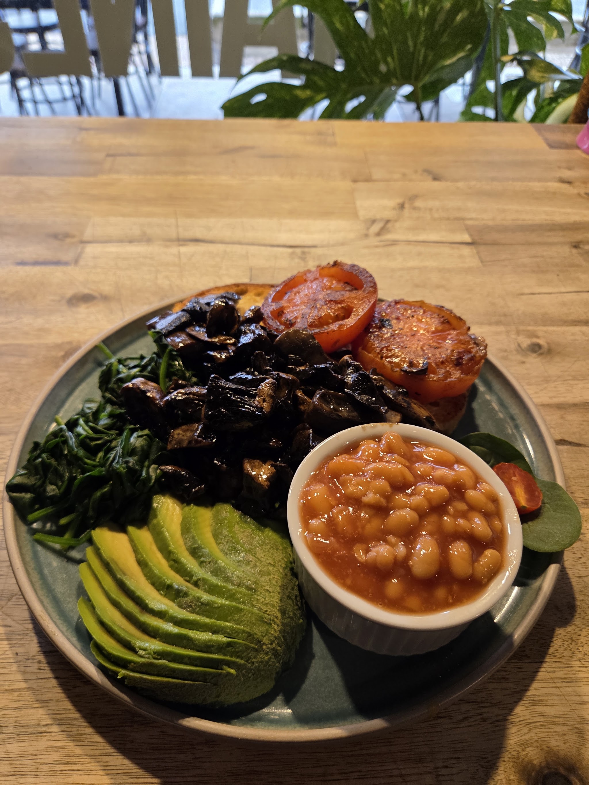 Vegetarian big breakfast with mushrooms, spinach, avocado, grilled tomato and baked beans