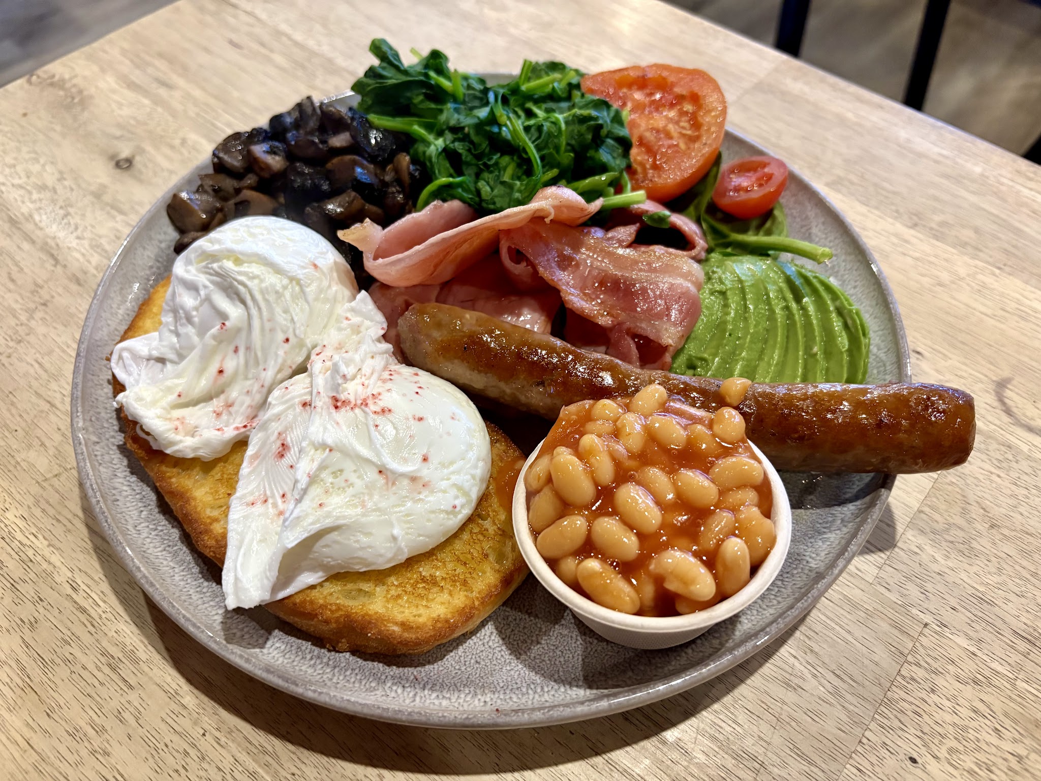 Big breakfast with poached eggs, bacon, sausage, mushrooms, avocado and baked beans